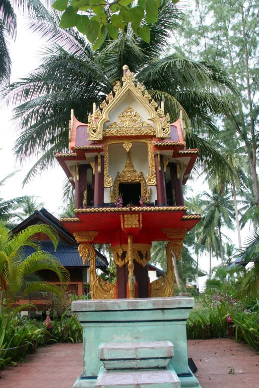 an ornate temple on a cement platform at the bottom of a garden
