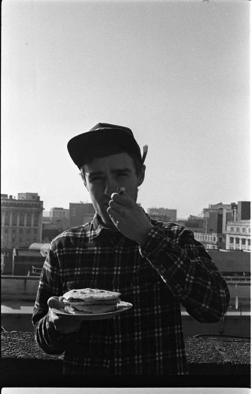 a young man eating food while standing outside