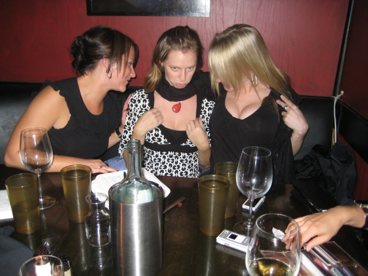 three pretty young ladies at a table using their cell phones