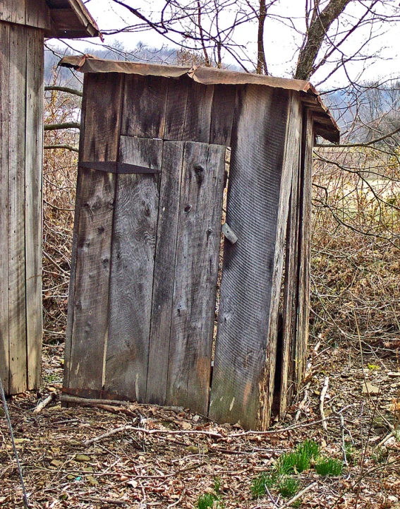 two old wood outhouses and one rusty wooden one