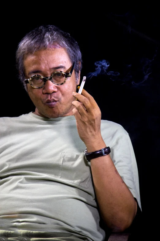 an older man sitting down with his cigarette in hand