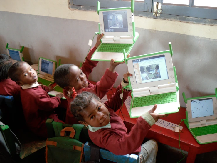 four children sit with their laptops in front of them
