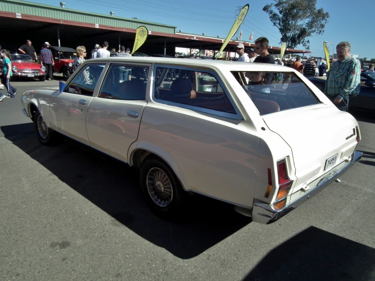 people standing around the front end of an old car