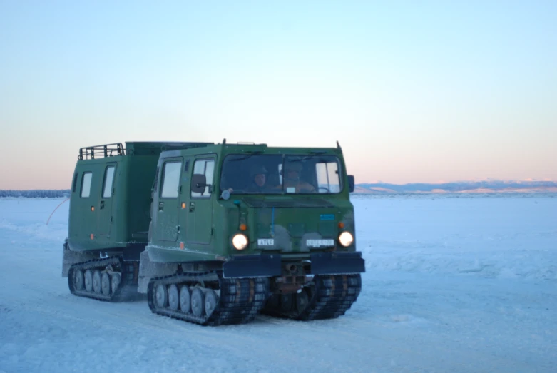 two army vehicles are sitting together in the snow