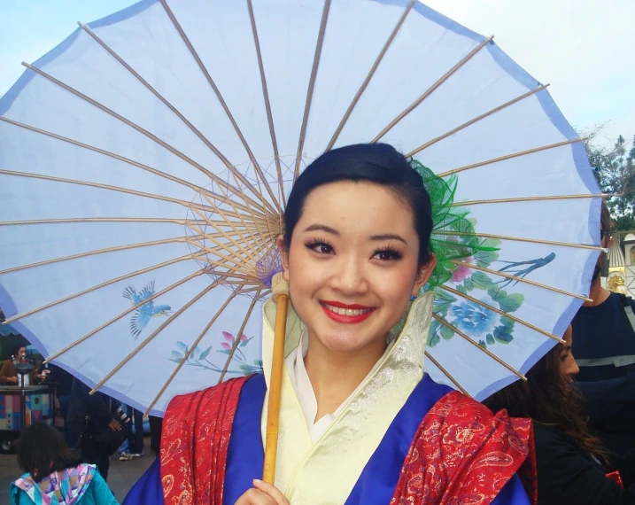 a pretty woman in chinese clothing holding an oriental umbrella