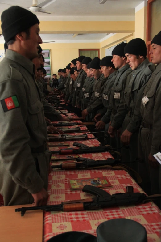 a group of soldiers in uniforms stand behind long tables that have red checkered paper on them