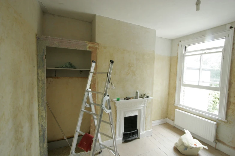 a room with a fireplace, ladder and window in it