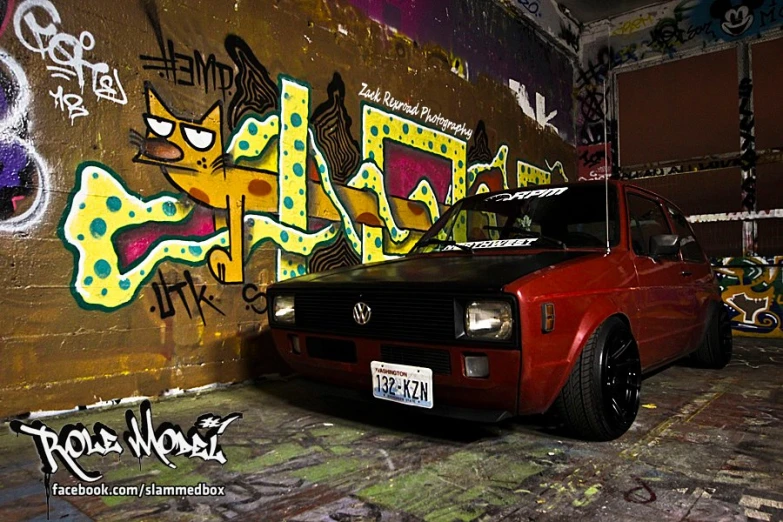 a volkswagen is parked against a wall covered in graffiti