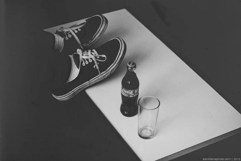 an empty bottle next to a pair of sneakers