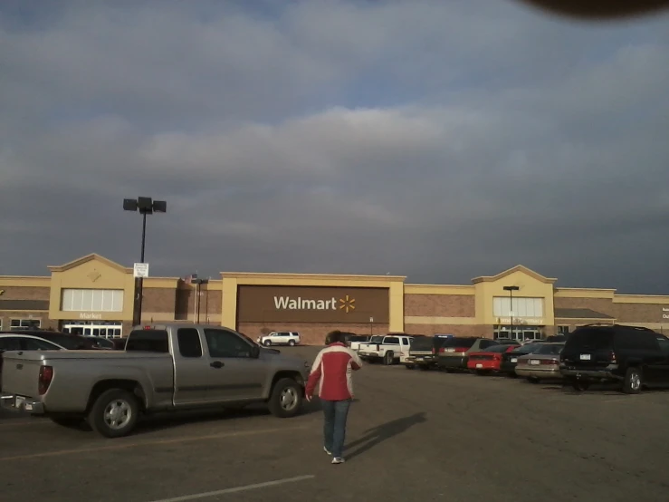 a woman in a red sweater standing in front of a walmart parking lot