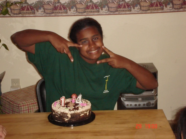 a boy posing for a picture behind a birthday cake