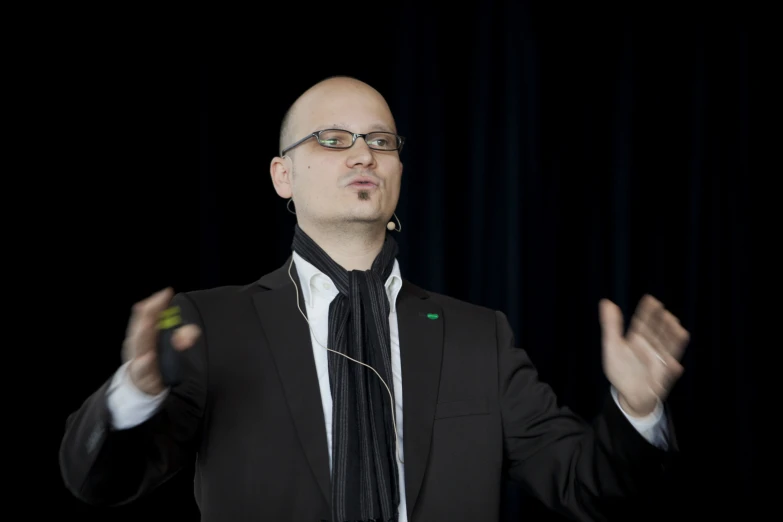 a bald man wearing glasses is speaking