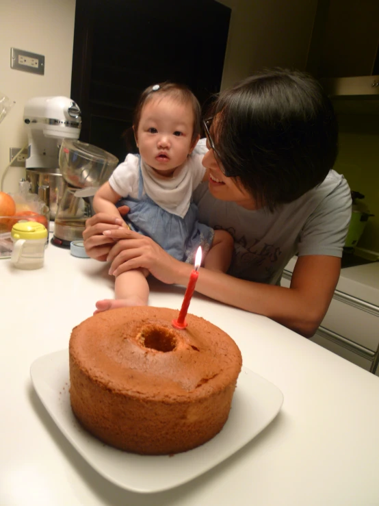 an adult with a child sit in front of a cake