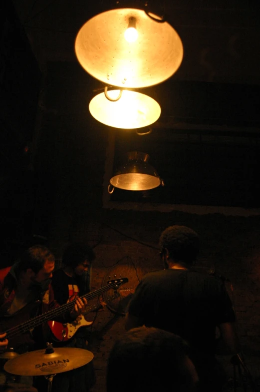 some people playing instruments under a light bulb