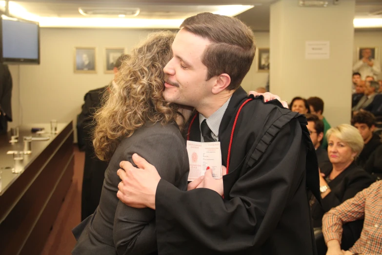 a man and a woman hug during a graduation ceremony