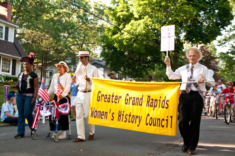 people marching down the street carrying yellow banners