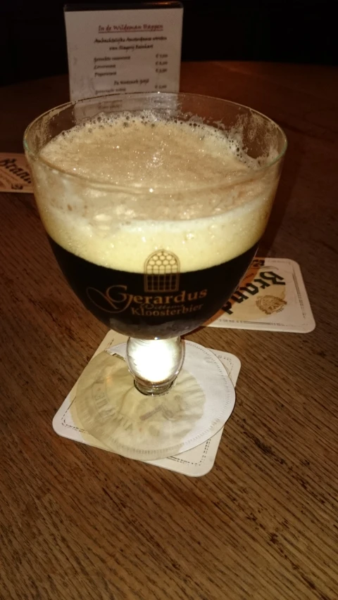 a dark glass with beer sitting on top of a table