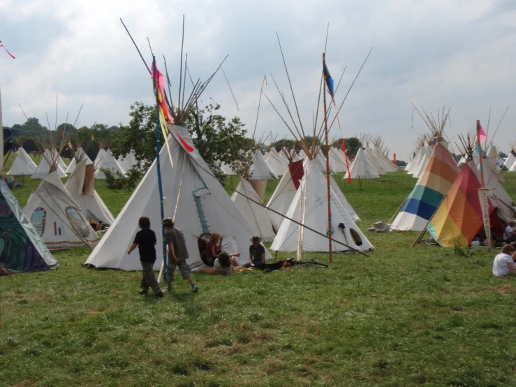 children sitting on the grass at a teepee