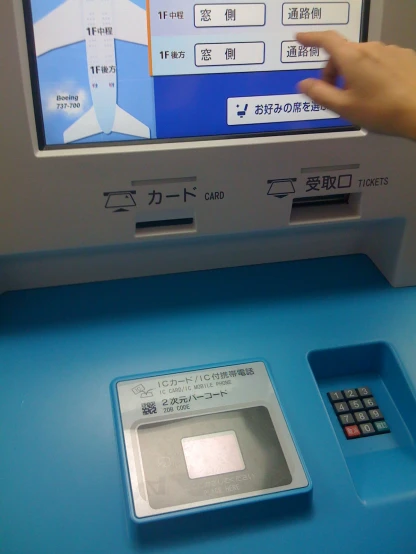 a hand reaches for an atm card on top of a atm