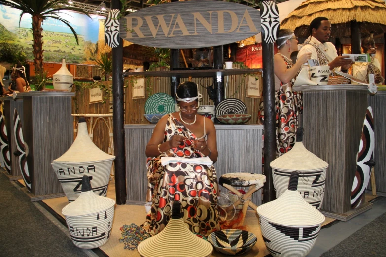 woman sits on a stool next to ceramic pottery