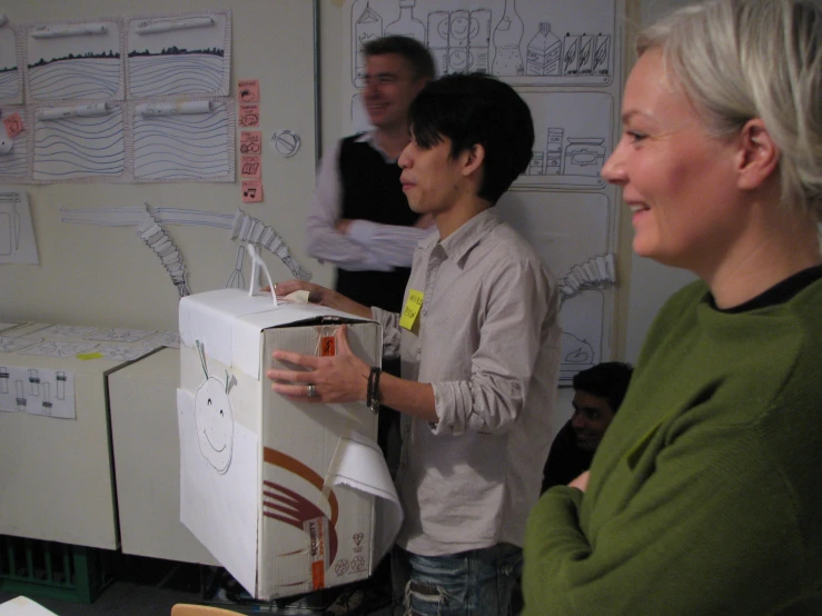 people standing in front of a refrigerator with pictures on the wall