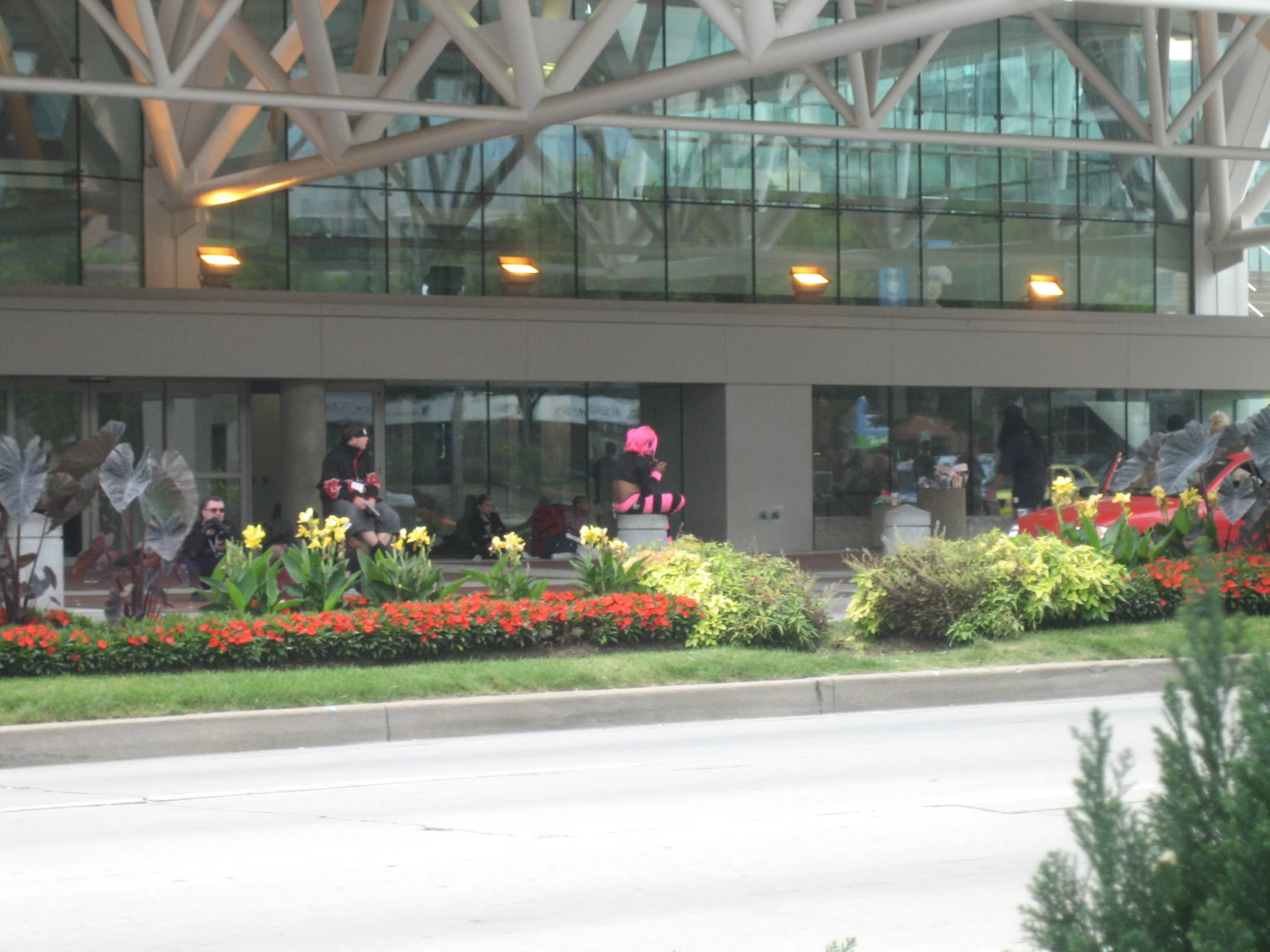 people are outside of a building with flowers and bushes