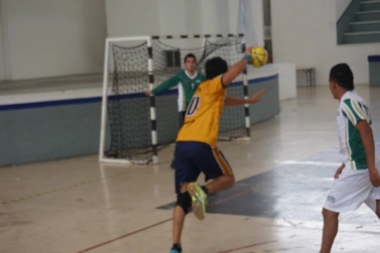 two men playing soccer inside an indoor gym