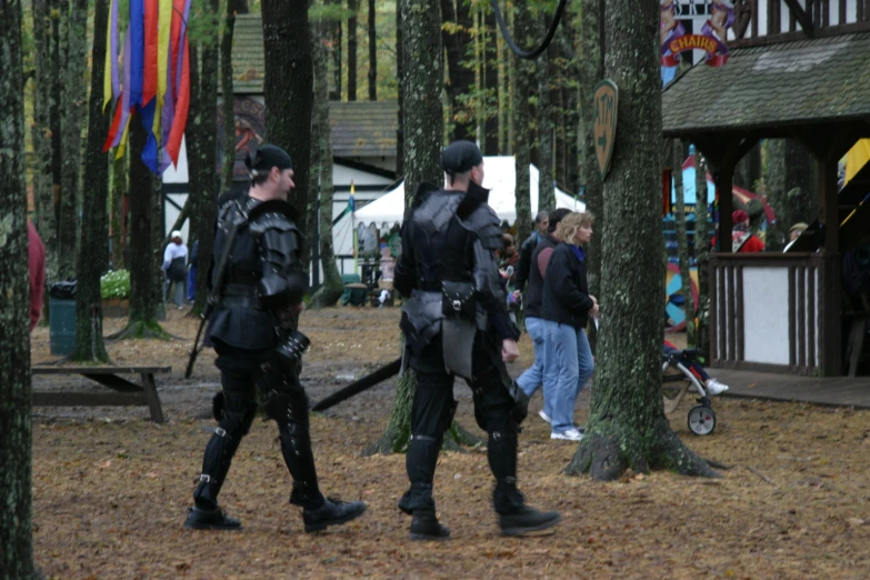 two men dressed in armor walking through the woods