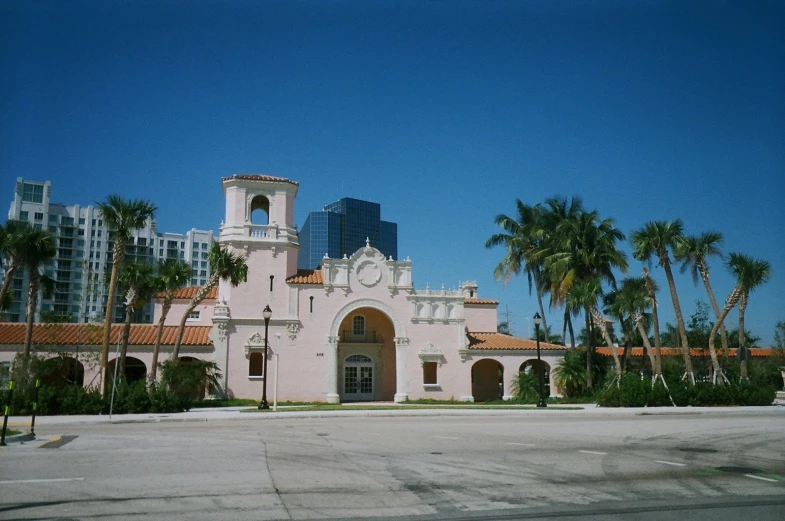 a tall building with a tower and palm trees in front of it