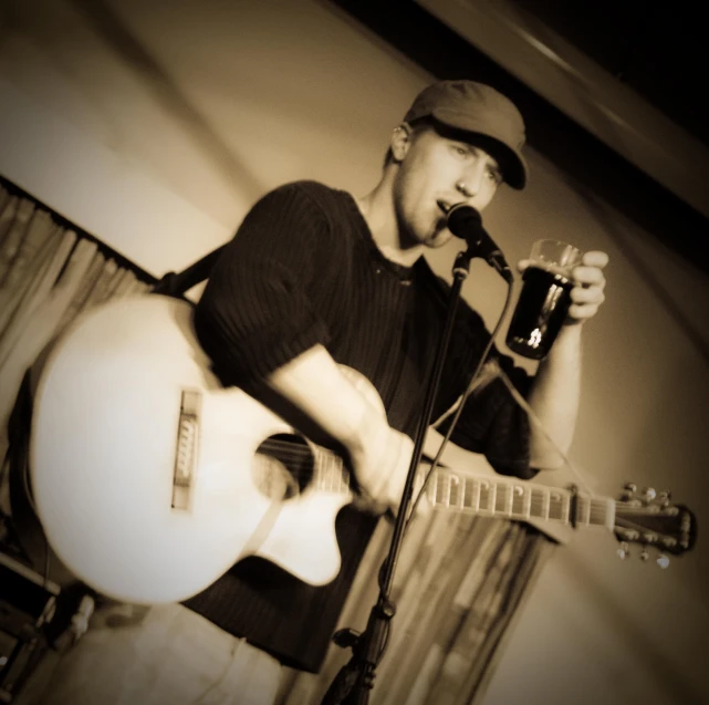 a young man playing the guitar while wearing a cap