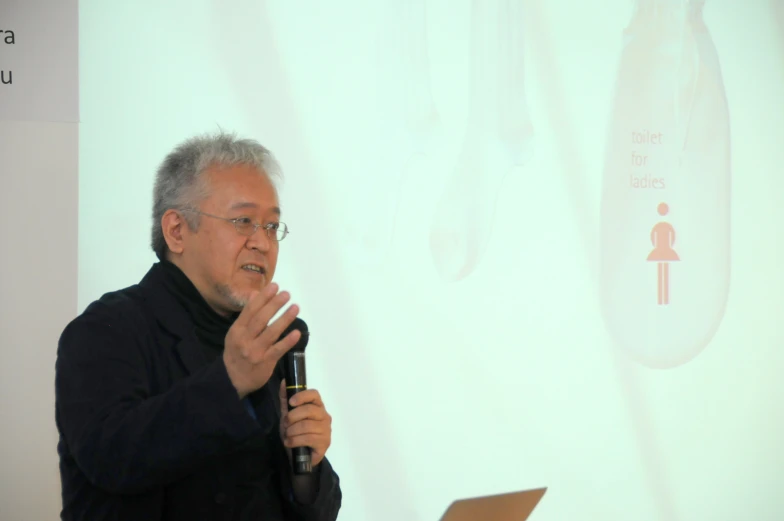 a man holding a microphone while speaking to a crowd