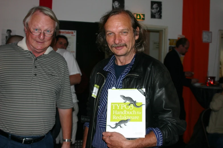 an older man holding a book with a bearded look