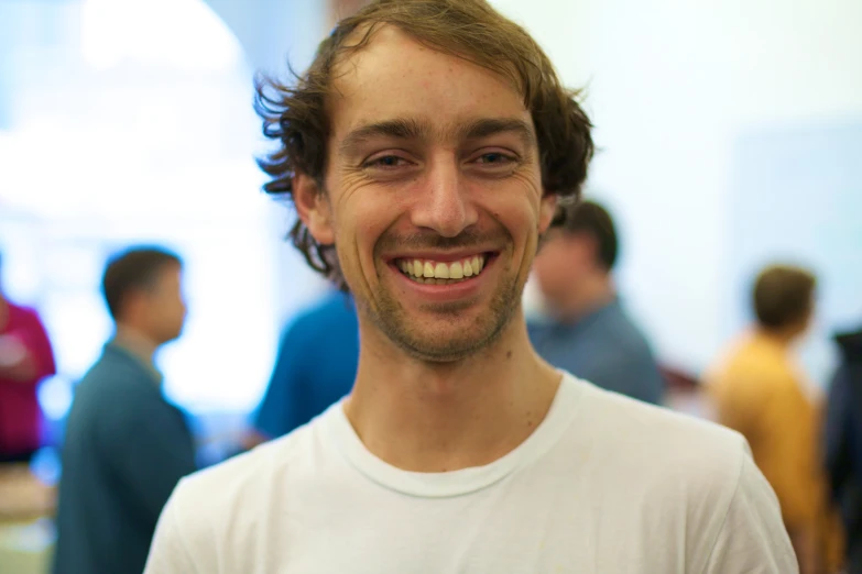 a smiling young man standing with other people behind him