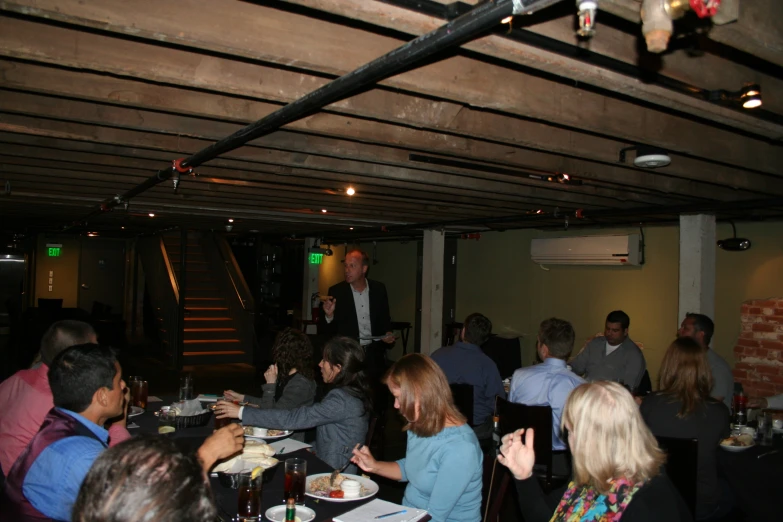 several people are sitting and standing in a dark room