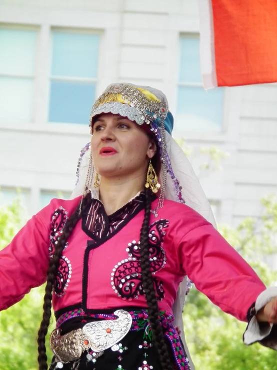 a woman wearing colorful attire and beads holds her hand out