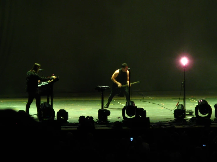 two men singing on stage in front of a microphone