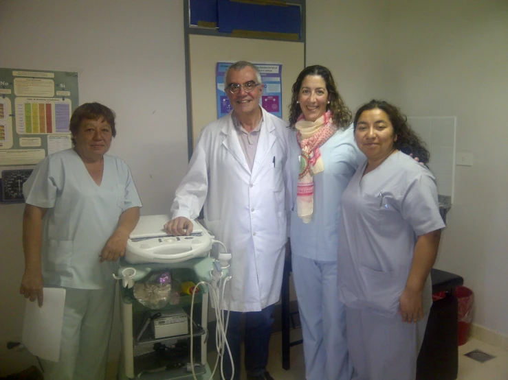 some people in scrubs standing by a hospital room machine