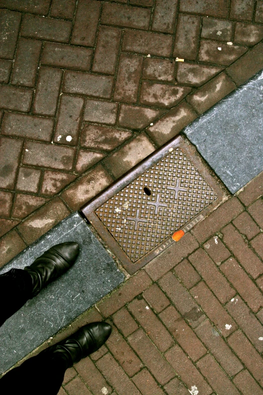 a man standing on sidewalk next to street drain