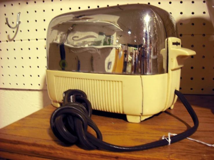 a yellow and silver toaster sitting on a wooden shelf