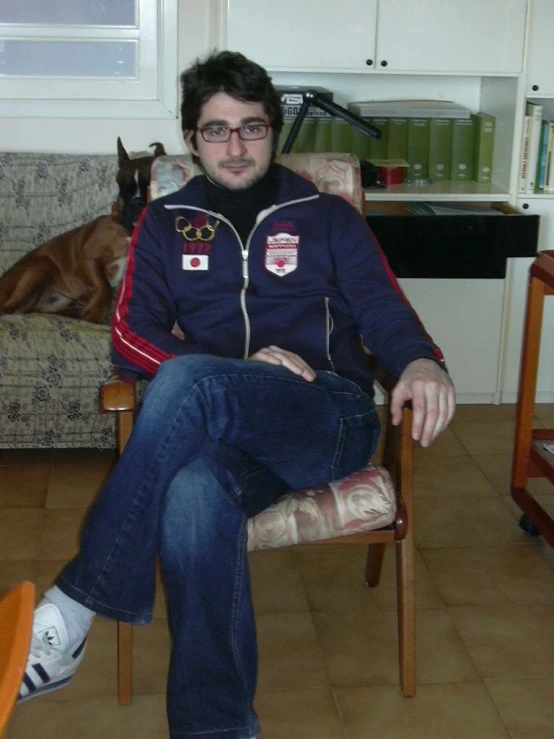 a man sitting in a chair next to a dog on the floor