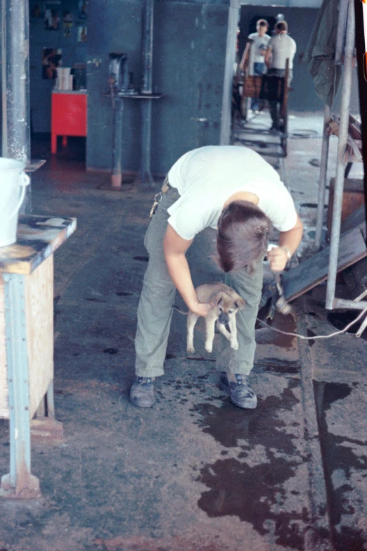 the man is holding a small dog by the water