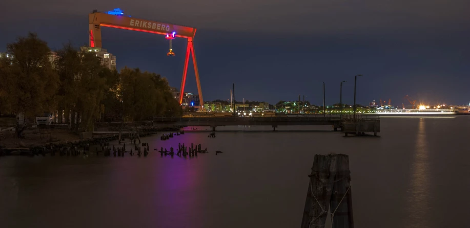 a boat sitting in a harbor with lights on and a crane overhead