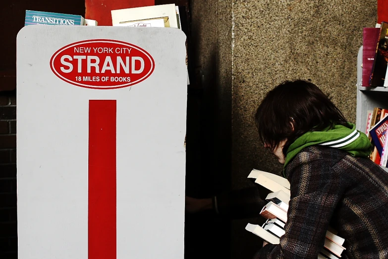 a young person leaning against a red and white stand