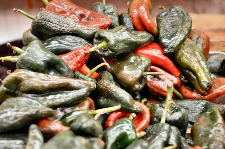 a pile of peppers sitting on top of a wooden table