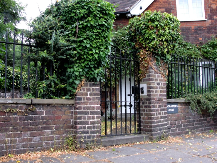 brick gate and brick house in front of gate and plants