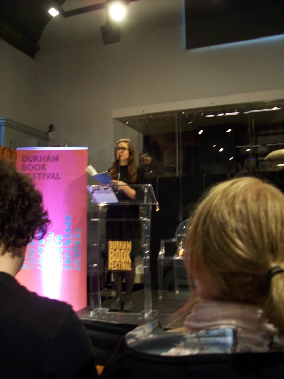 the woman in black speaks at a podium with a microphone