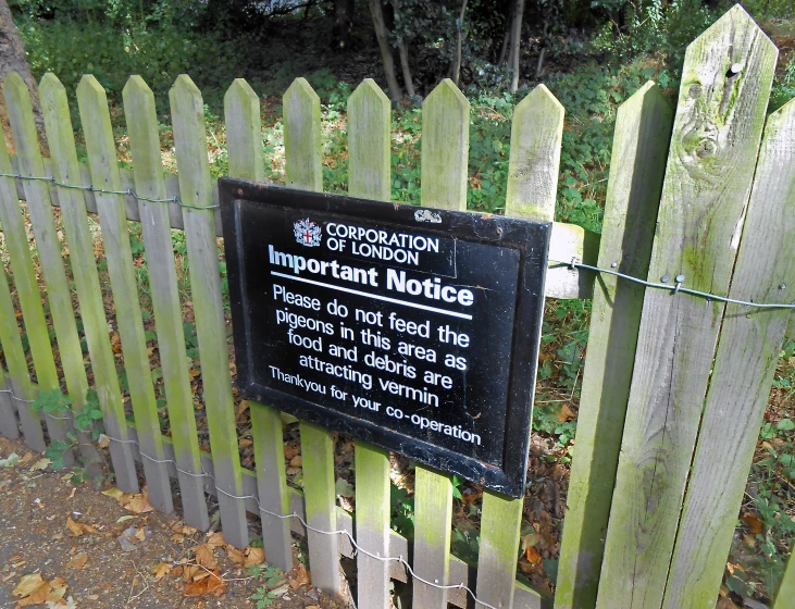 a sign for a wooden fence near a forest