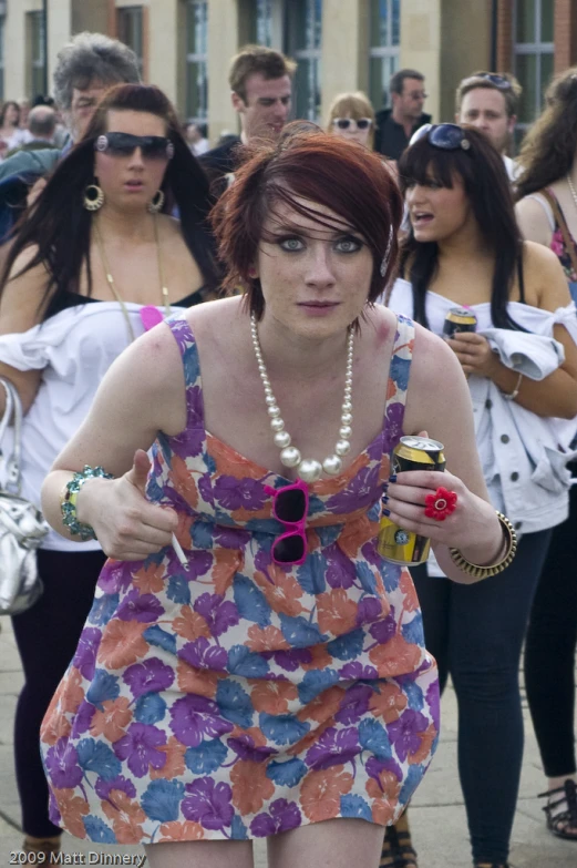 a woman walking down the street in a dress and necklace