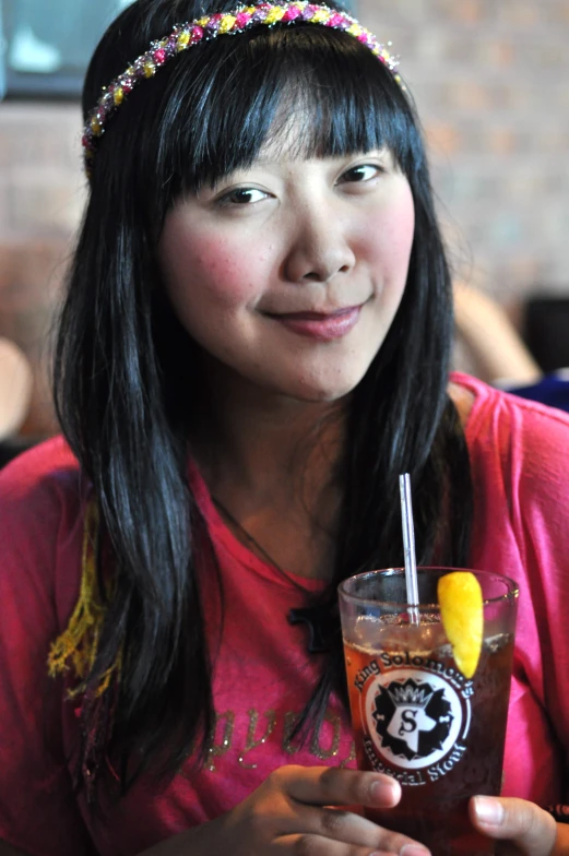 a woman sitting at a table holding up a beverage