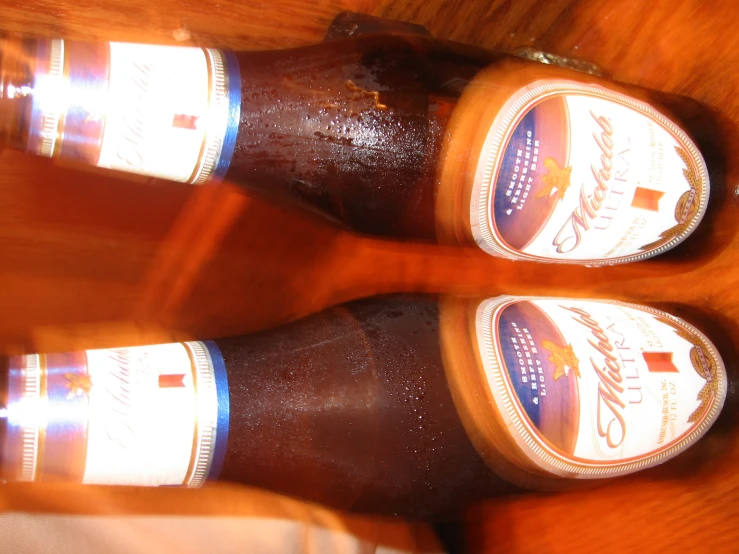 two bottles with beer sitting on a table